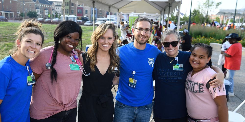 Healthcare workers and a young participant at a health outreach event.