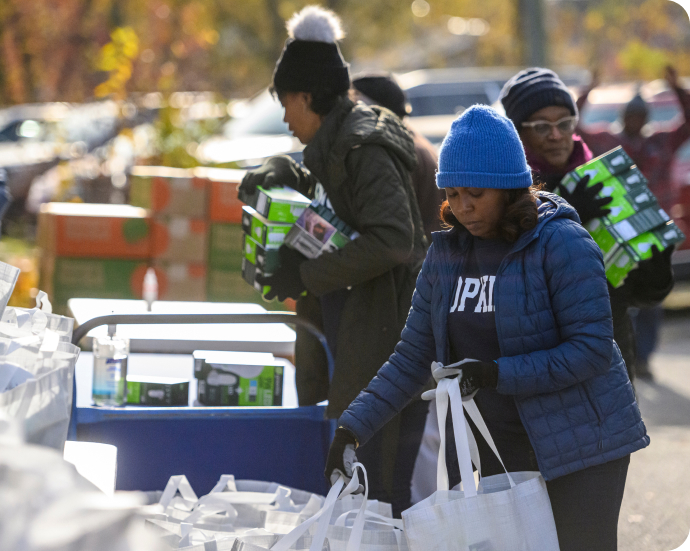 Volunteers packing items into white bags at an outdoor event.