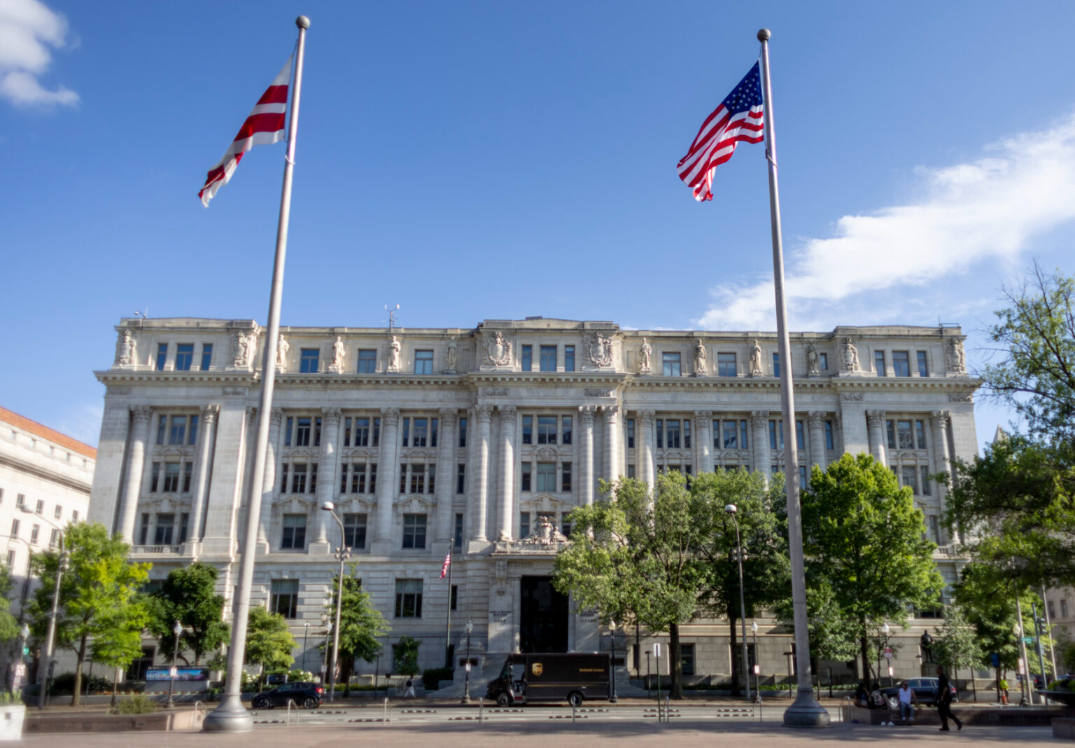 John A. Wilson Building with U.S. and D.C. flags in front, under clear blue sky.