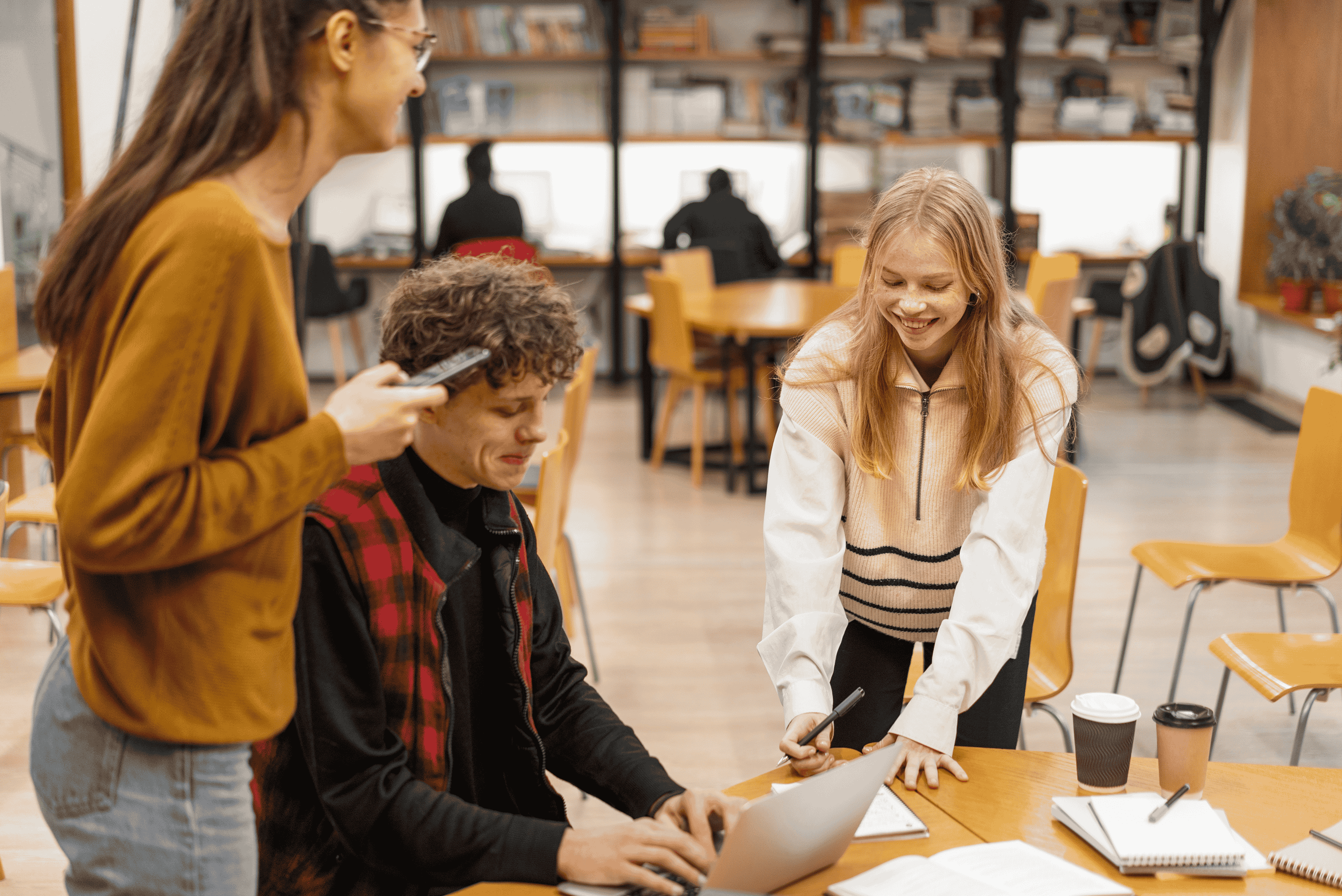 Group of students smiling and studying in a shared workspace